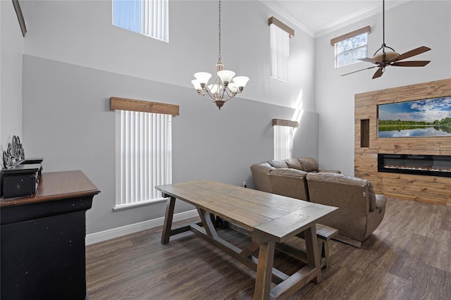 dining area featuring a glass covered fireplace, crown molding, wood finished floors, and baseboards