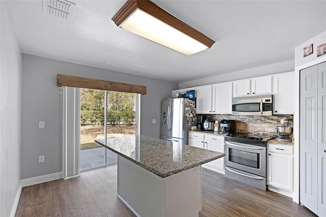 kitchen featuring visible vents, stone countertops, dark wood-style flooring, stainless steel appliances, and decorative backsplash