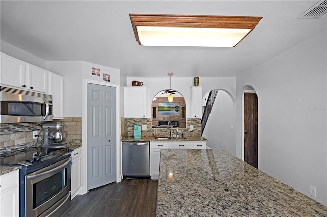 kitchen featuring a sink, stainless steel appliances, arched walkways, and white cabinets