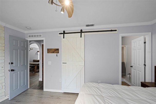 bedroom featuring visible vents, wood finished floors, and ornamental molding