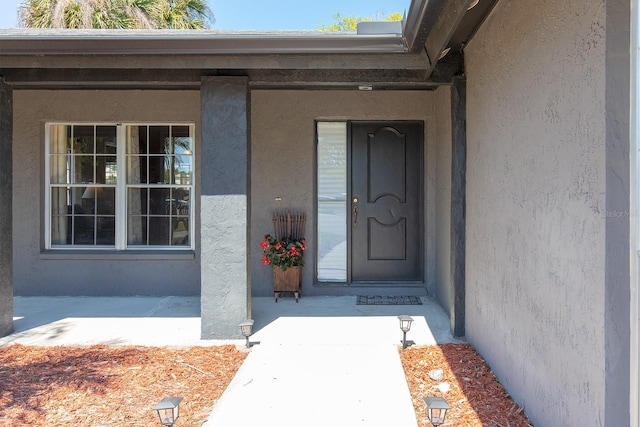 doorway to property featuring stucco siding