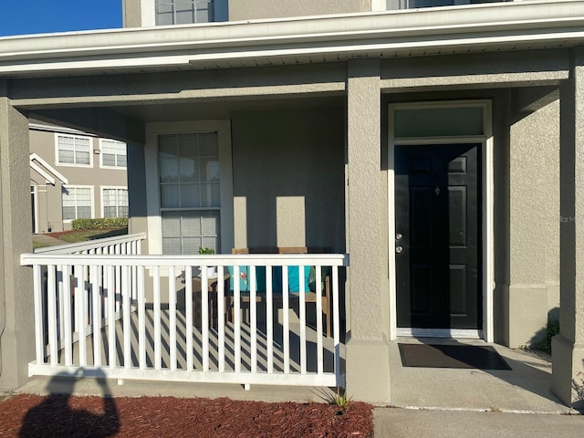 entrance to property with covered porch and stucco siding