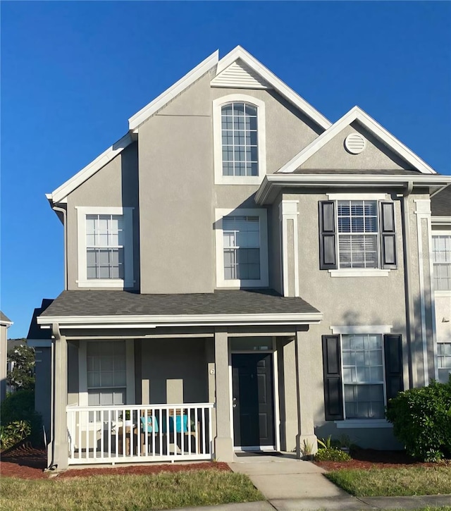 traditional-style home featuring stucco siding and covered porch