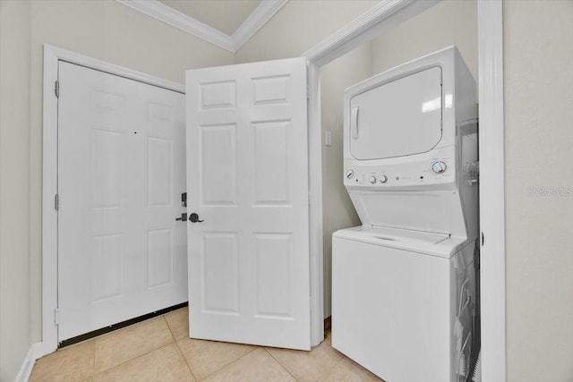 laundry room with light tile patterned floors, laundry area, crown molding, and stacked washer and dryer