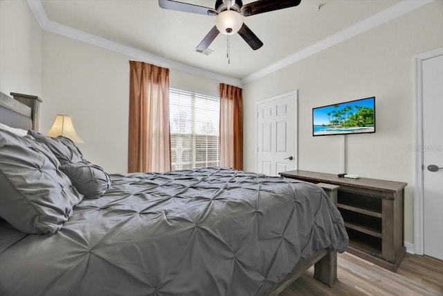 bedroom with visible vents, wood finished floors, ceiling fan, and ornamental molding