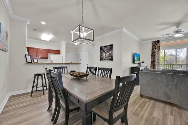 dining area with light wood-style flooring, baseboards, ornamental molding, and ceiling fan with notable chandelier