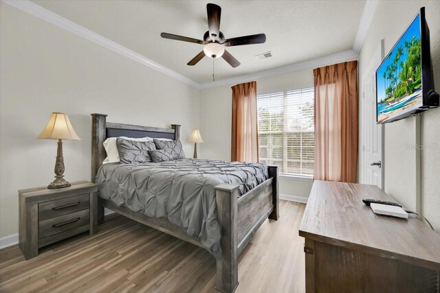 bedroom with visible vents, baseboards, crown molding, and light wood-style floors