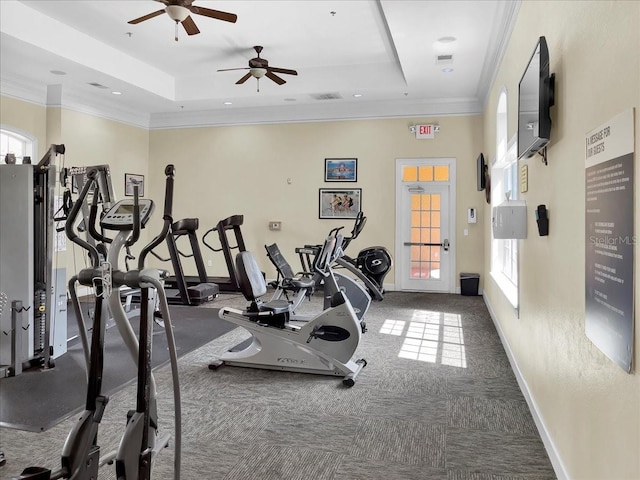 workout area featuring baseboards, a raised ceiling, visible vents, and ornamental molding