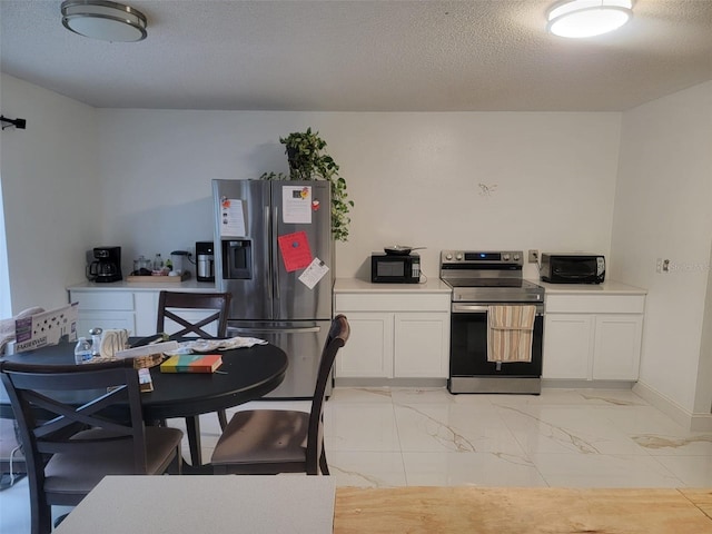 kitchen with light countertops, white cabinets, appliances with stainless steel finishes, a textured ceiling, and marble finish floor