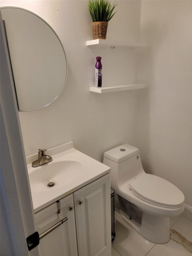 half bath with toilet, marble finish floor, and vanity