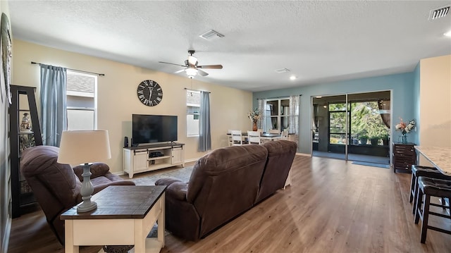 living room featuring wood finished floors, visible vents, and a textured ceiling