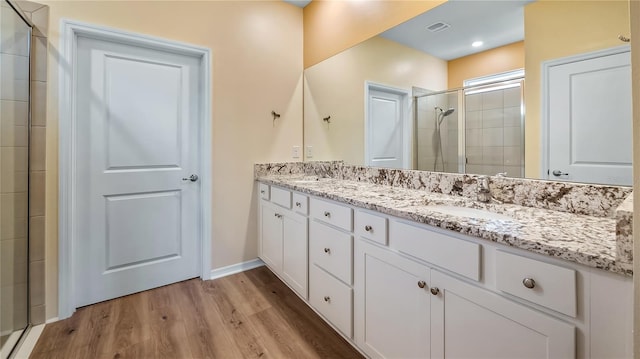 full bath featuring double vanity, a shower stall, wood finished floors, and a sink