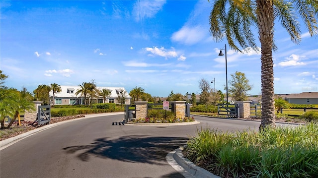 view of street featuring curbs, street lights, a gated entry, and a gate