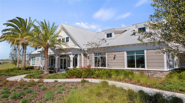 rear view of house featuring stone siding, french doors, and metal roof