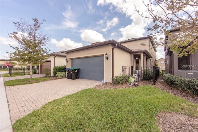 view of front of house featuring fence, a front yard, stucco siding, decorative driveway, and a garage