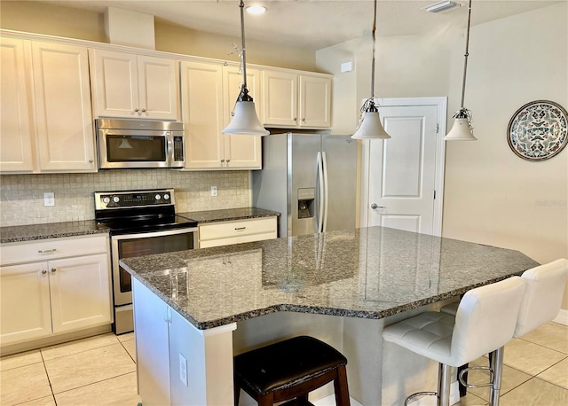 kitchen with a kitchen island, decorative backsplash, stainless steel appliances, and light tile patterned flooring