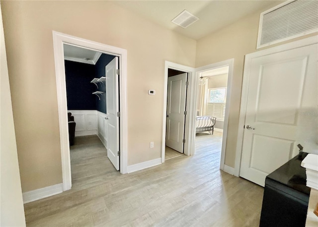 hall featuring light wood-type flooring, visible vents, and baseboards