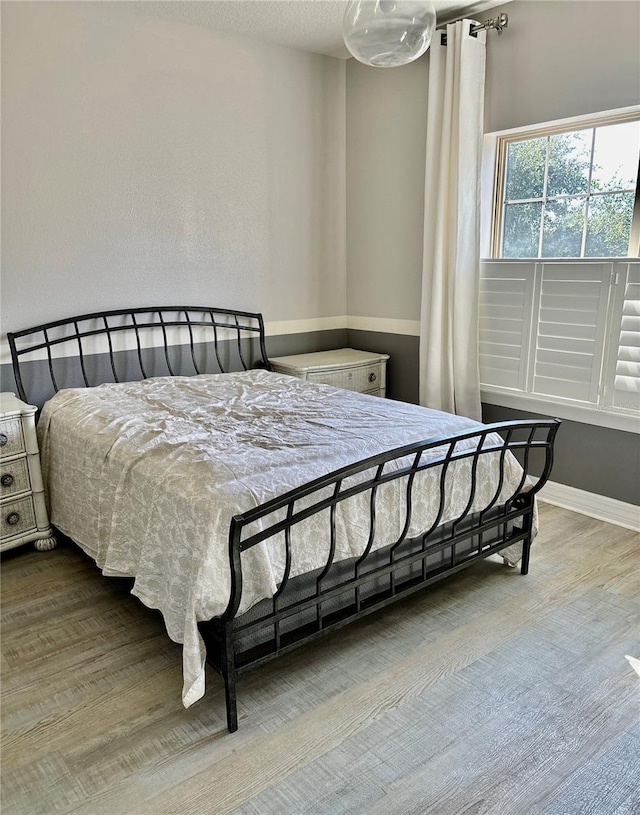 bedroom with baseboards and wood finished floors