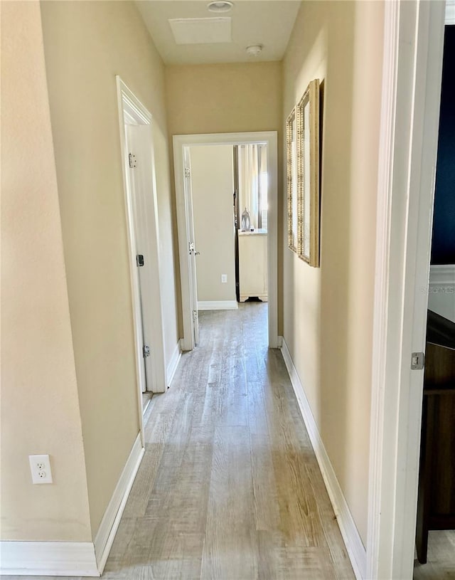 hall featuring light wood-style floors and baseboards