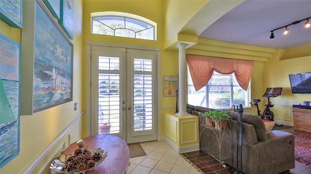 doorway to outside with french doors, decorative columns, rail lighting, and tile patterned flooring