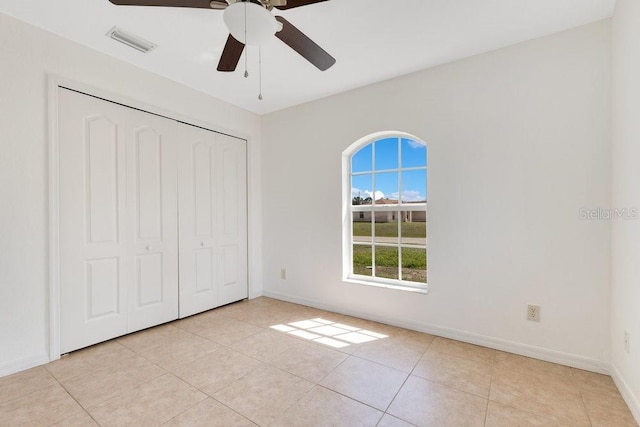 unfurnished bedroom featuring light tile patterned floors, baseboards, visible vents, and a closet