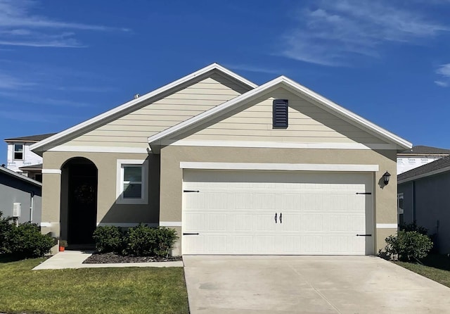 ranch-style house with concrete driveway, an attached garage, a front yard, and stucco siding