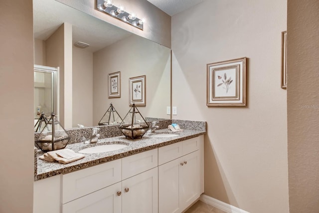 bathroom with double vanity, baseboards, and a sink