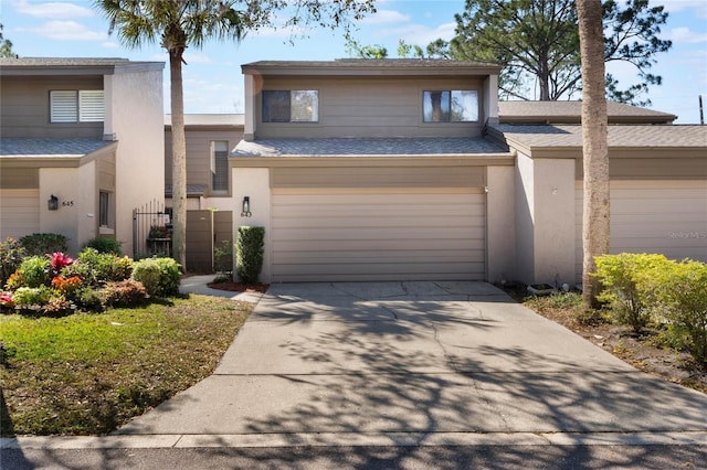 view of front of property featuring stucco siding, concrete driveway, a garage, and roof with shingles