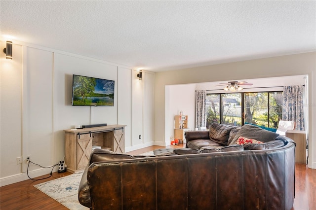 living area with a textured ceiling, a ceiling fan, and wood finished floors