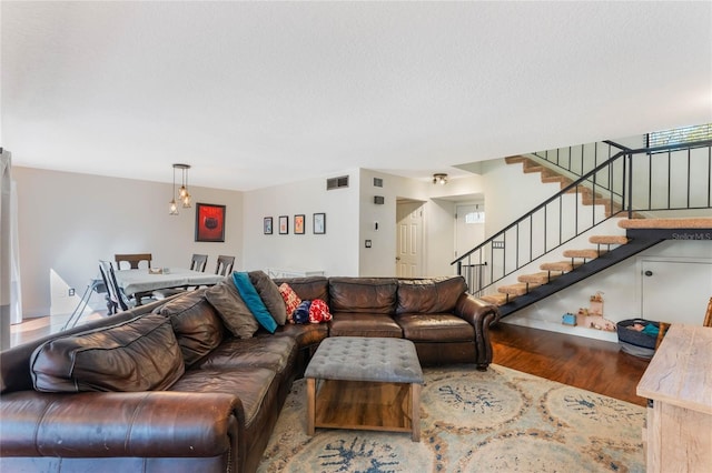 living room featuring visible vents, a textured ceiling, wood finished floors, and stairs