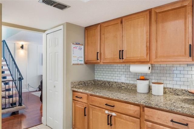 kitchen featuring light stone counters, visible vents, and backsplash