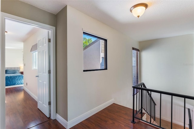 hall featuring baseboards, an upstairs landing, and wood finished floors