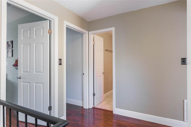 hall featuring visible vents, baseboards, and wood finished floors