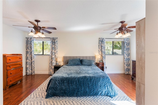 bedroom with multiple windows, wood finished floors, and baseboards