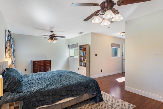 bedroom featuring a ceiling fan, wood finished floors, visible vents, and baseboards