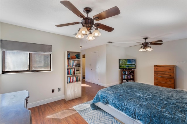 bedroom featuring visible vents, a ceiling fan, baseboards, and wood finished floors