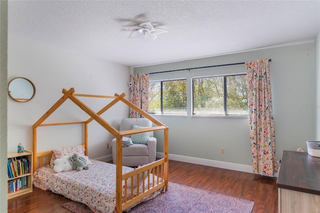 bedroom with baseboards, a textured ceiling, and wood finished floors