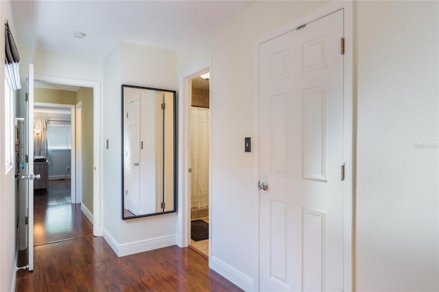 hallway featuring baseboards and dark wood-style flooring