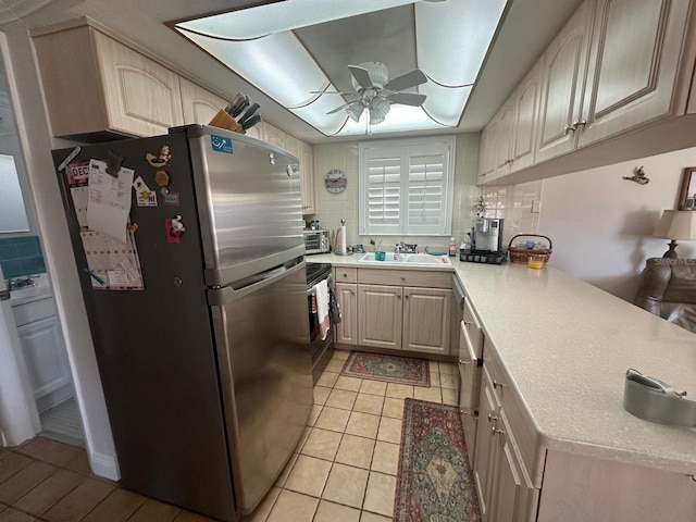 kitchen featuring a peninsula, a sink, decorative backsplash, light countertops, and stainless steel appliances