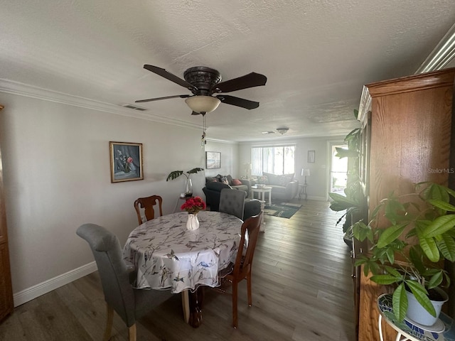 dining area with a textured ceiling, crown molding, baseboards, and wood finished floors