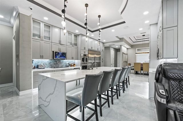 kitchen featuring a large island, appliances with stainless steel finishes, a raised ceiling, and ornamental molding