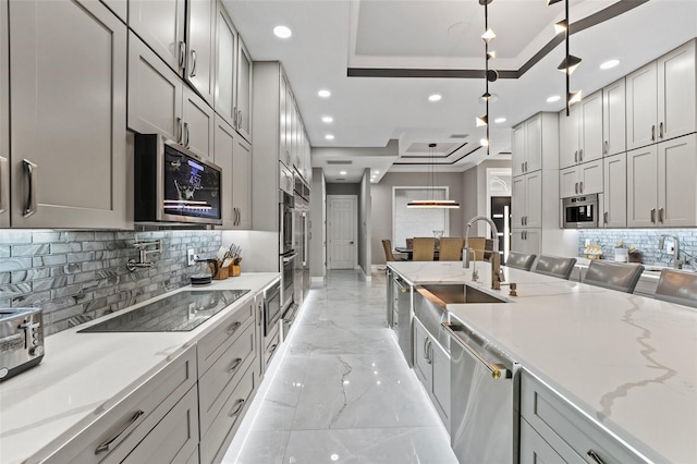 kitchen featuring recessed lighting, hanging light fixtures, appliances with stainless steel finishes, a raised ceiling, and marble finish floor