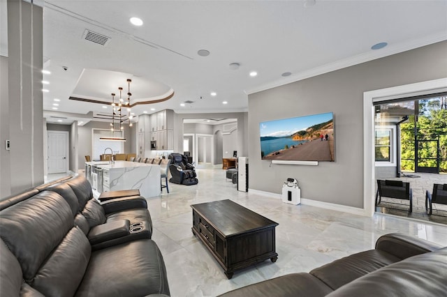 living room with baseboards, visible vents, a tray ceiling, ornamental molding, and a chandelier