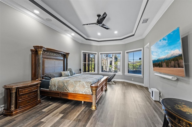 bedroom with visible vents, baseboards, ornamental molding, wood finished floors, and a raised ceiling