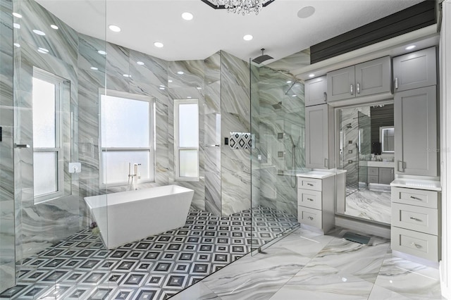 bathroom with a freestanding tub, marble finish floor, a marble finish shower, tile walls, and vanity