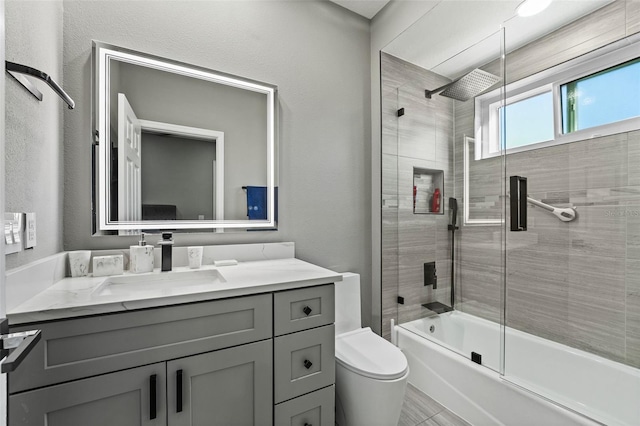 full bath with vanity, toilet, and bath / shower combo with glass door