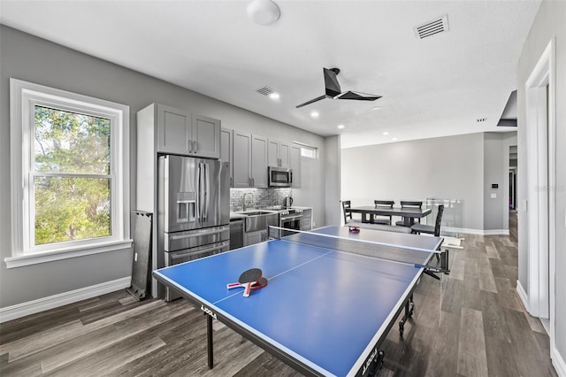 rec room featuring dark wood-style floors, visible vents, a ceiling fan, and baseboards