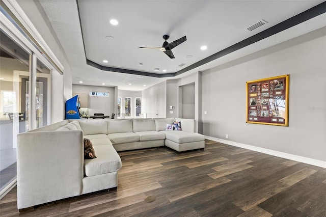 living area featuring a tray ceiling, baseboards, visible vents, and wood finished floors