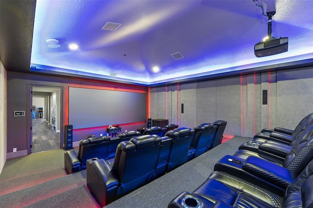 cinema room featuring a raised ceiling, visible vents, and carpet floors