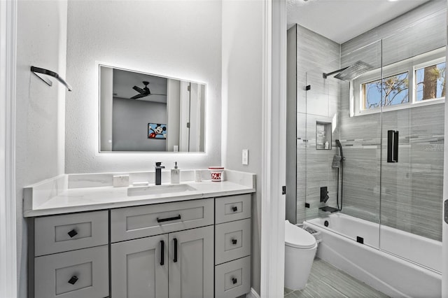 bathroom with vanity, toilet, a textured wall, and enclosed tub / shower combo